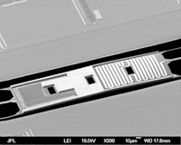 The detector shown in this electron-beam micrograph works by converting the light from the cosmic microwave background into heat in a meandered resistor.  A Titanium film tuned on its transition to a superconducting state makes a sensitive thermometer to measure this heat.  The resistor and thermometer are located on an island of material, suspended in free space on tiny fibers made by a process called micro-machining.  The sensors are cooled to just 0.25 degrees above absolute zero to minimize thermal noise. (<i>Anthony Turner, JPL</i>)